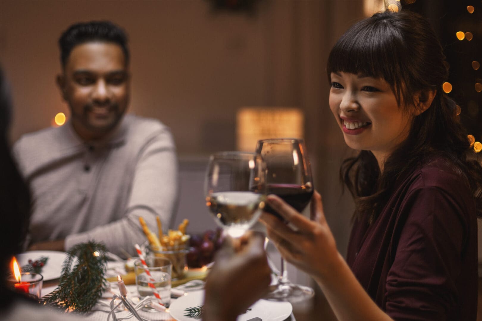 A woman holding a glass of wine while sitting at the table.