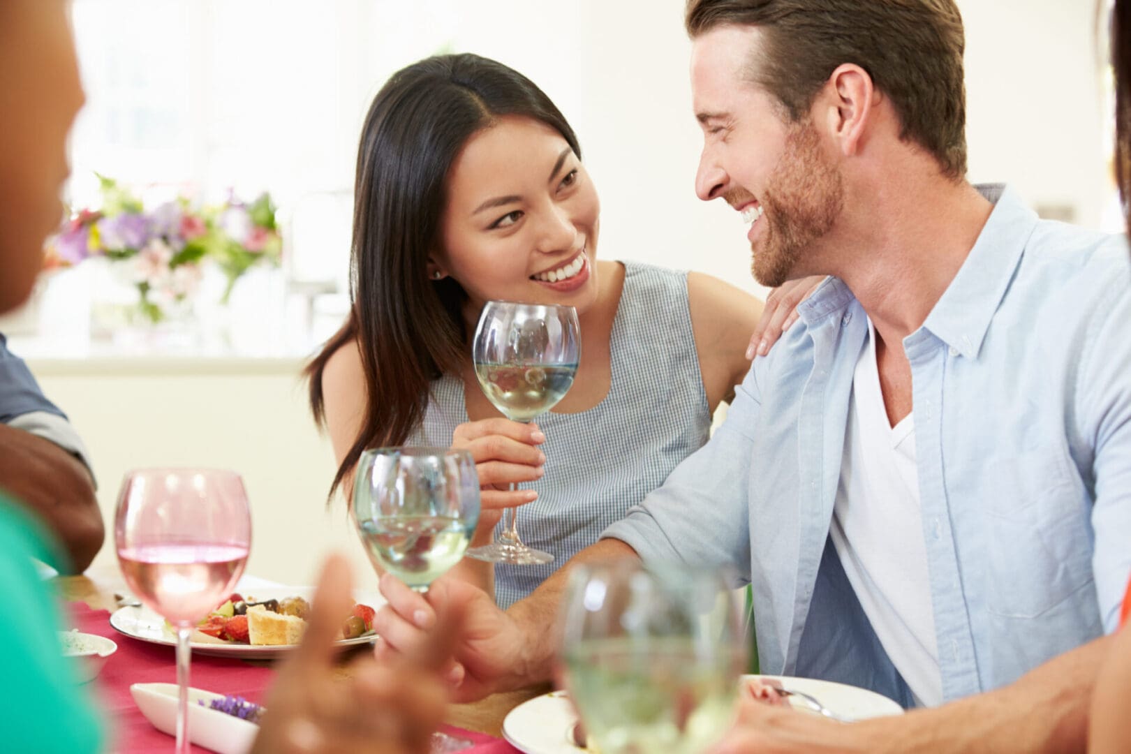 A man and woman sitting at the table with wine glasses.